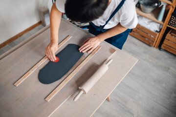 Top view of potter using scraper for flattening clay surface at studio