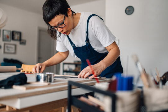 Artistic craftswoman measuring flatten clay at ceramics studio.
