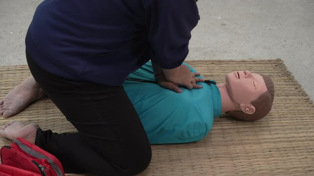 A woman studies at a gas station with an adult CPR dummy on the floor. She practices situation assessment skills, staying safe, and life-saving techniques for choking and CPR.