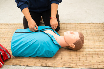A woman studies at a gas station with an adult CPR dummy on the floor. She practices situation assessment skills, staying safe, and life-saving techniques for choking and CPR.