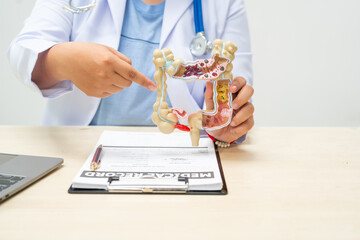 A female doctor sits at a table in a hospital, discussing intestinal health issues, including...