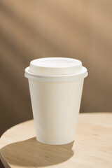 The solitary coffee cup on the wooden table symbolizes the fast-paced urban lifestyle and its environmental impact, highlighting the disposable culture.