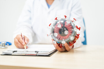 A female doctor sits at a table in a hospital, discussing the COVID-19 virus.She explains the...