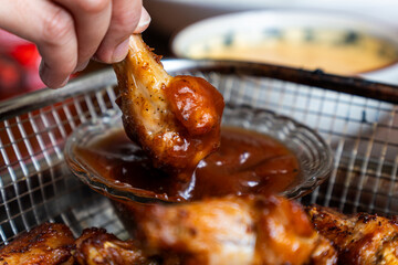 dipping chicken wing in spicy barbeque sauce