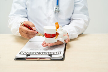 A female doctor sits at a table in a hospital, discussing spine conditions like scoliosis,lumbar...
