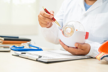 A female doctor at a desk in a hospital, discussing eye diseases such as color blindness,...