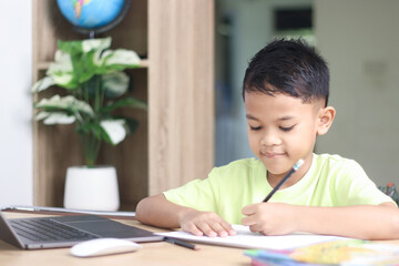 A Happy little asian boy studying online learning class with online video call zoom teacher at home. E-learning or Home schooling education concept.