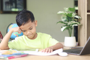 A Happy little asian boy studying online learning class with online video call zoom teacher at home. E-learning or Home schooling education concept.