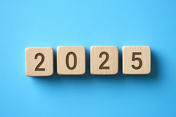 Wooden cubes spelling the word 2025 on a blue background, new year, new strategy concept