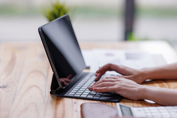 Businesswomen or Asian Accountants using calculator and a tablet laptop computer to analyze...