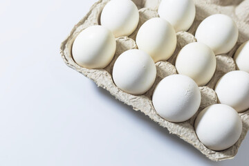 White eggs in a carton box on a white background.