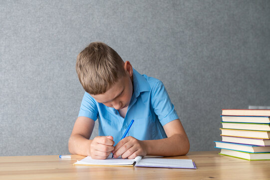 Young Boy Concentrating on Writing Homework in Notebook. World Dyslexia Awareness Day