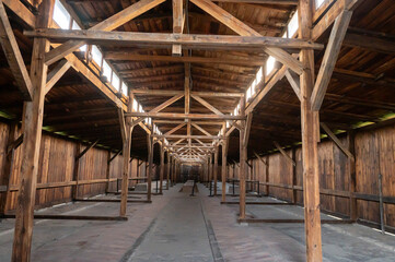 Interior view of an empty wooden barn with structural beams and a high ceiling.