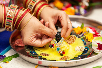An Indian woman adorns (Laddu Gopal), a Hindu god 'Krishna', after performing a ceremonial bath...