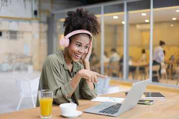 African American young woman using laptop with wear headphones.