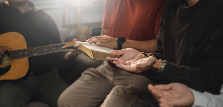 Christians and prayers Group of Christians holding hands praying for faith and Bibles on wooden table for prayer meeting. Sit and pray.