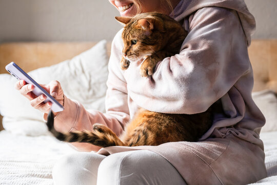 Woman making video call while holding a cat. Relaxation and companionship at home.