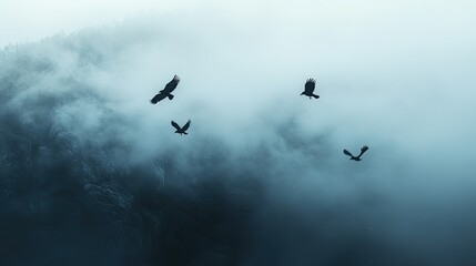Fototapeta premium A small flock of crows flying over a foggy landscape, with the misty sky above creating an eerie atmosphere with space for text.