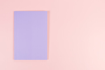 Top view of purple notebook on pink background. School, office wallpaper. Flat lay, copy space.