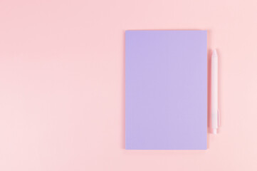 Top view of purple notebook, pink pen on pink background. School, office wallpaper. Flat lay, copy space.	
