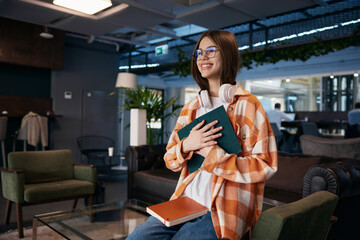 Attractive teenage girl reading work book in comfortable modern office