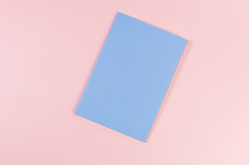 Fototapeta premium Top view of blue notebook on pink background. School, office wallpaper. Flat lay, copy space. 