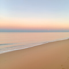 Obraz premium A tranquil beach with soft sand and gentle waves at dawn.