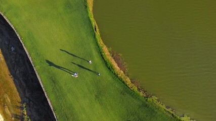 Coach teaching a girl and her brother to play golf in summer in a luxury course