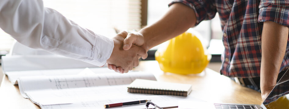 Client shaking hands with contractor after confirm blueprint to renovate house.