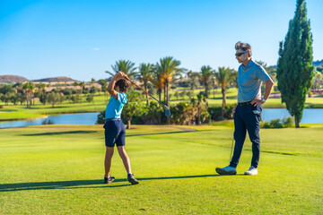 Golf instructor teaching hot to play to a boy
