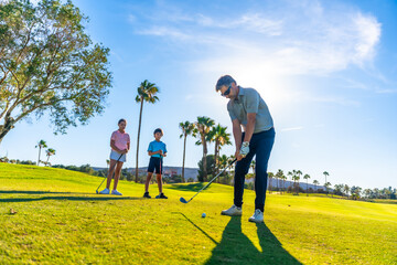 Fototapeta premium Man teaching how to swing golf to two children