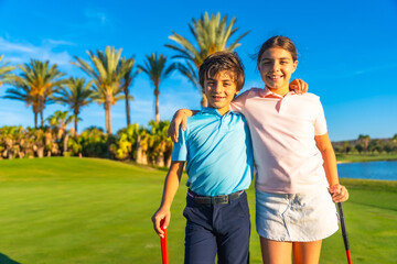 Two kids embracing during golf lessons in a green course