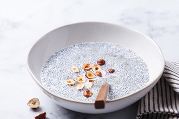 Chia pudding with hazelnuts and maple syrup, white background.
