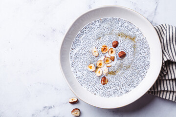 Chia pudding with hazelnuts and maple syrup, white background.