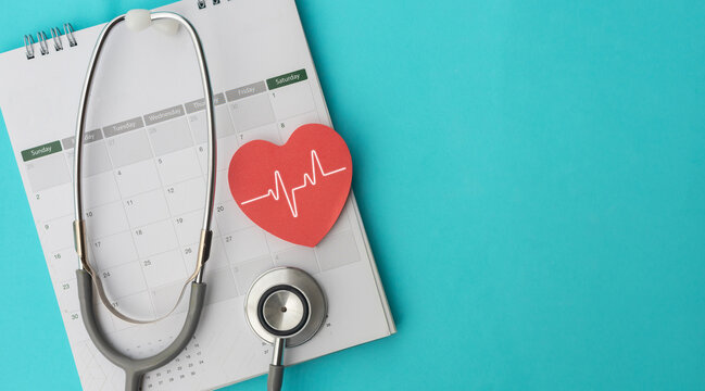 close up top view on red heart symbol and stethoscope on calendar with over blue background for design about ads or banner of doctor appointment and health checkup following personal lifestyle concept