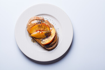 Peanut butter toast with peach and seeds.