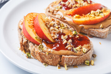 Peanut butter and jam jam with peach and nuts, white background.