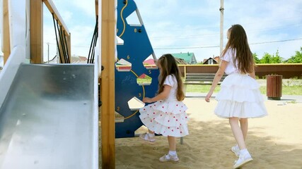 Adorable little girls plays on the playground. A children slides down a slide. Happy childhood concept