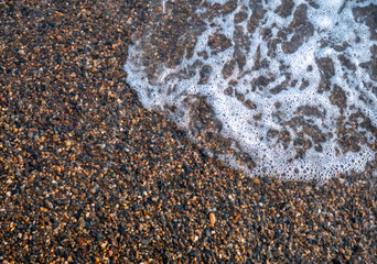 beach of small pebbles with a rolling wave