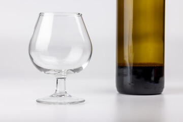 Horizontal shot of an empty wine glass and wine bottle in the center of a white background