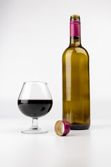 Elegant Vertical Wine Setup with Red Wine Glass, Empty Bottle, and Cork in Center