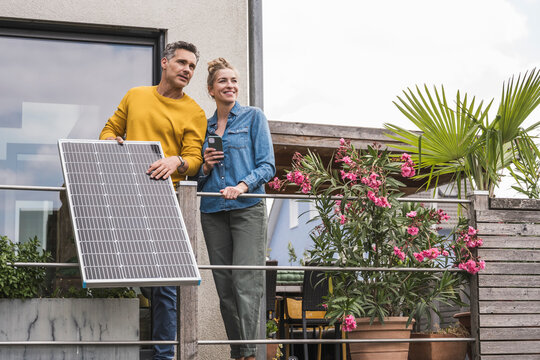 Couple installing solar panel on balcony