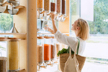 Woman filling lentils in glass jar at shop