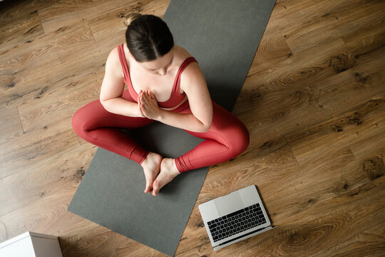 Instructor sitting on yoga mat and and teaching in online session at home
