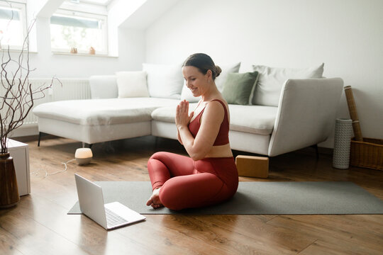 Smiling instructor teaching prayer pose in online yoga session at home