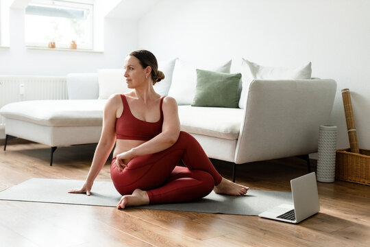 Woman practicing Paripurna Matsyendrasana pose on yoga mat at home