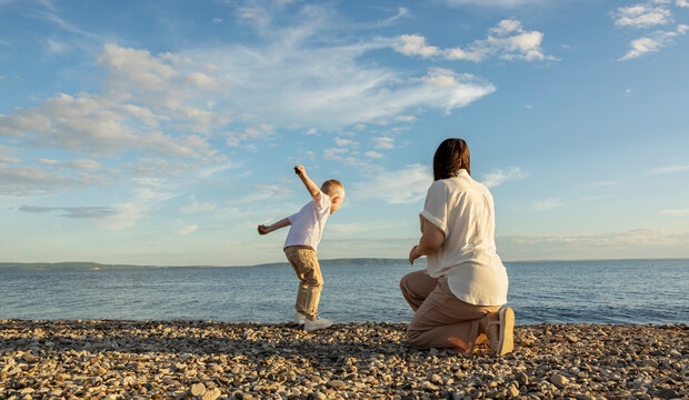 Mom and son spend time on the beach in the evening at sunset.