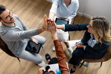 Business colleagues giving high-five to each other sitting in office