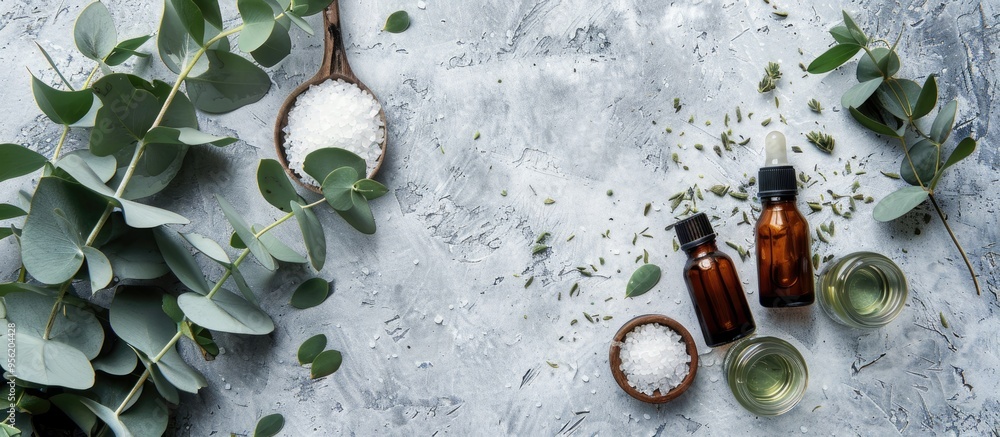 Poster essential oil bottles sea salt and eucalyptus branches on a grey background in a flat lay compositio