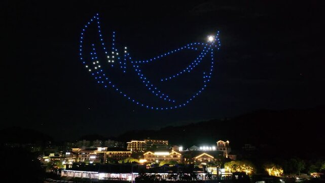 light show by drones over city at night